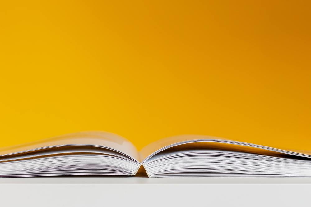 Open book on a table with yellow background